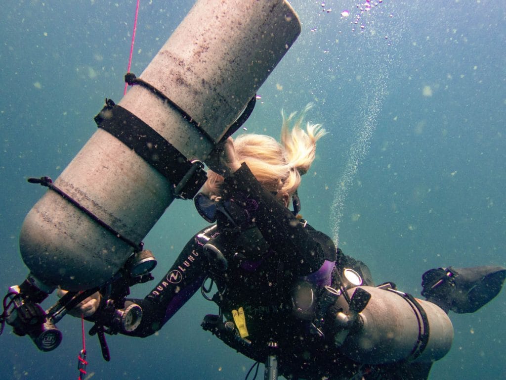 Sidemount diver cleaning up tank