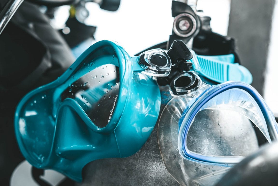 Two scuba masks hanging from a tank valve