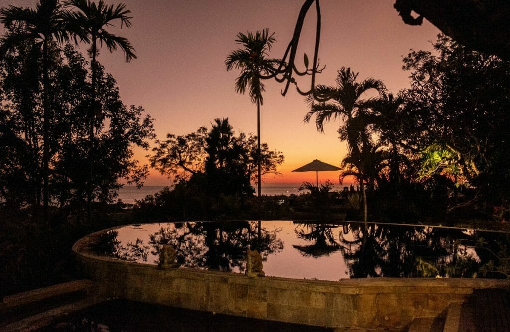 Sunrise and reflections of umbrella and palmtrees in a pool