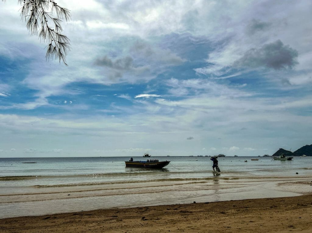 Dive boat with guy carrying tanks in Koh Tao's Sairee Beach